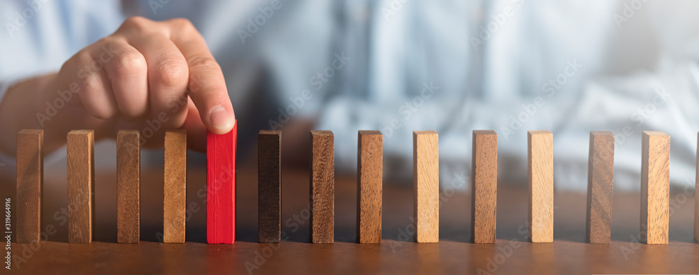 商业人士尝试在木桌上选择红色木块和深色背景商业组织sta