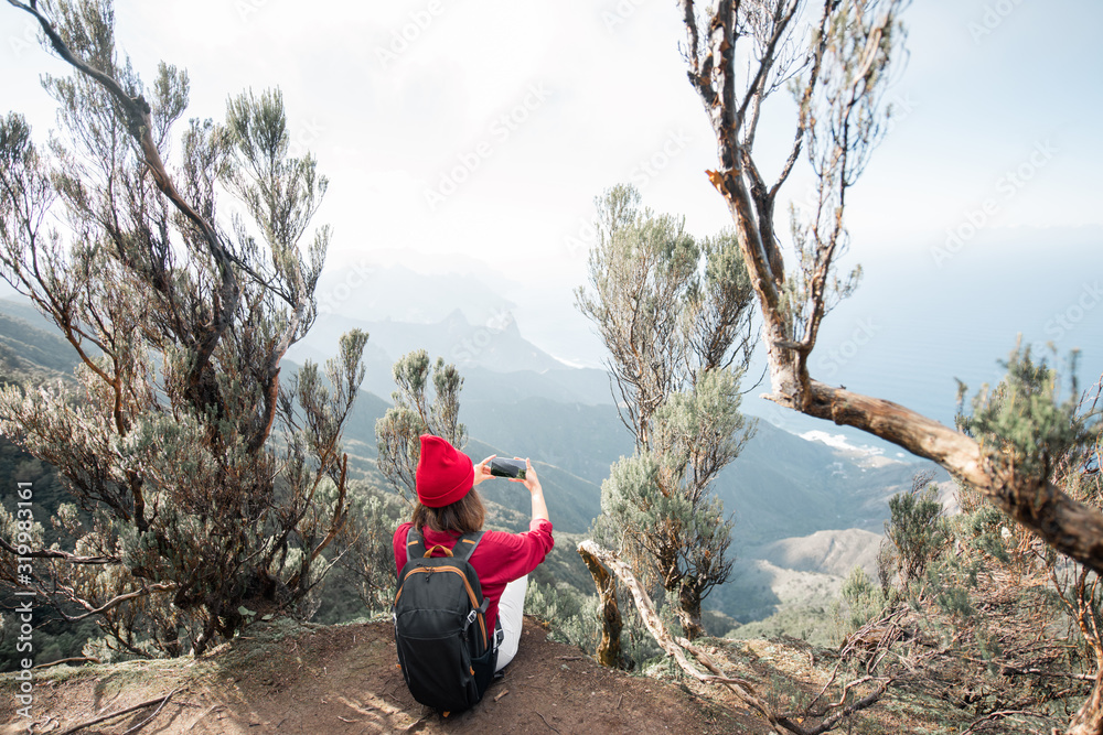 Woman enjoying breathtaking view on the rocky coastline of Tenerife island sitting above the precipi