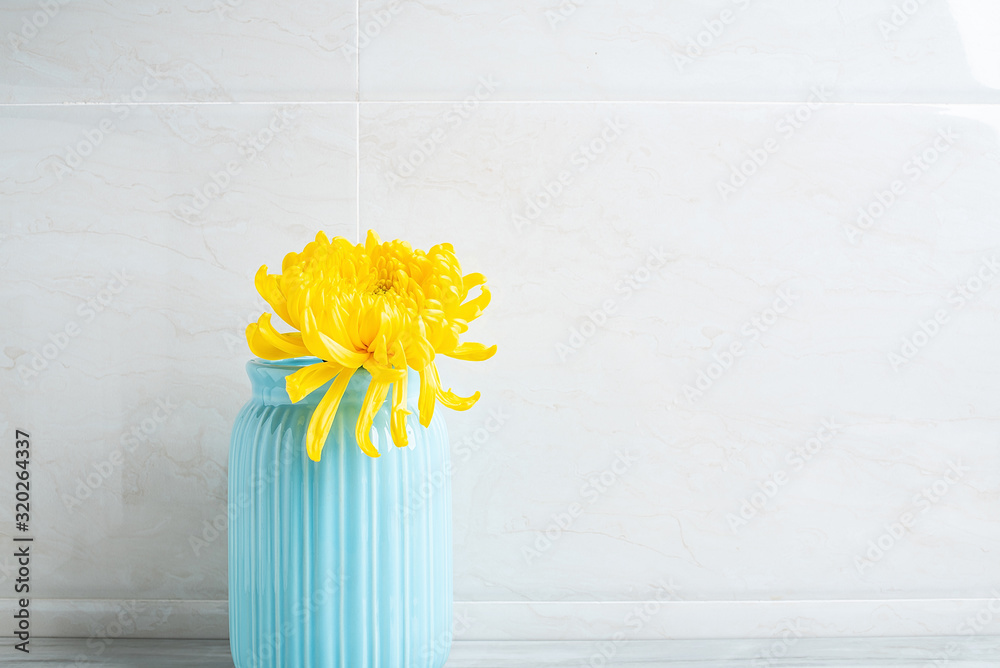 一瓶黄色菊花放在干净的浴室瓷砖台面上