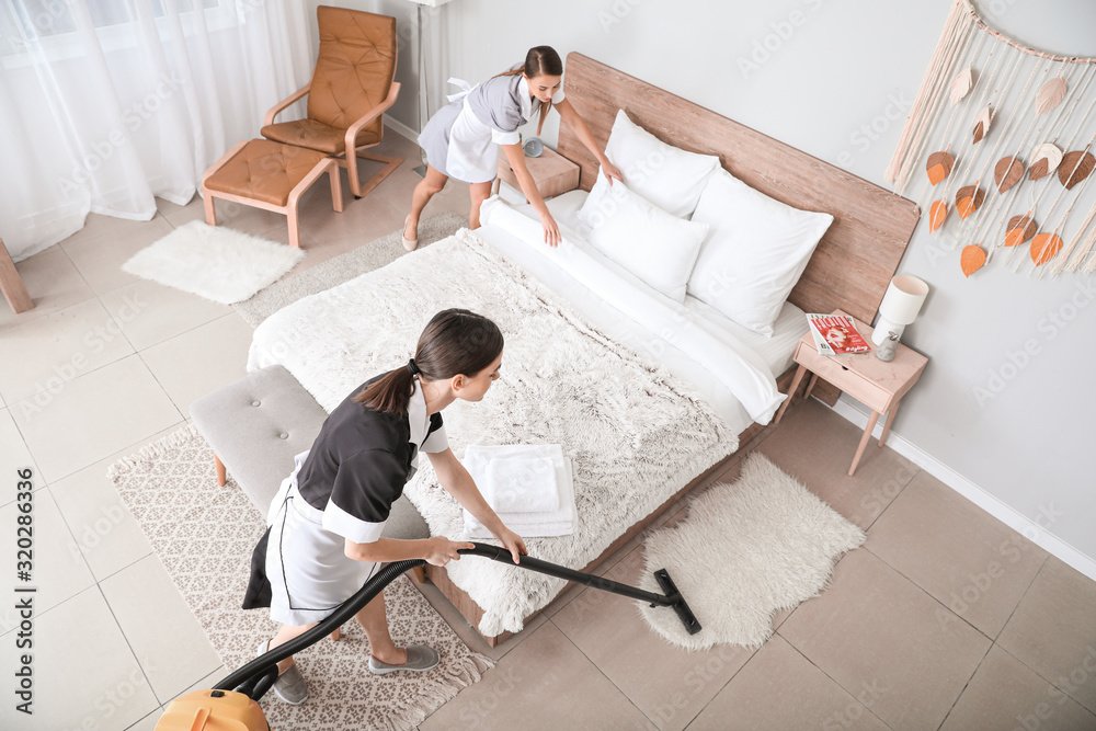 Beautiful chambermaids cleaning hotel room