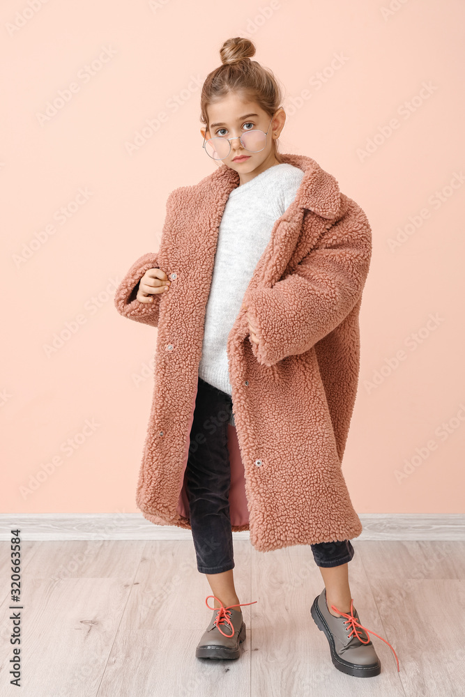 穿着冬装的可爱小女孩靠近彩色墙