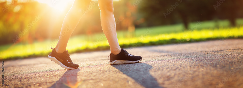 一名年轻女子在柏油路上的公园里跑步