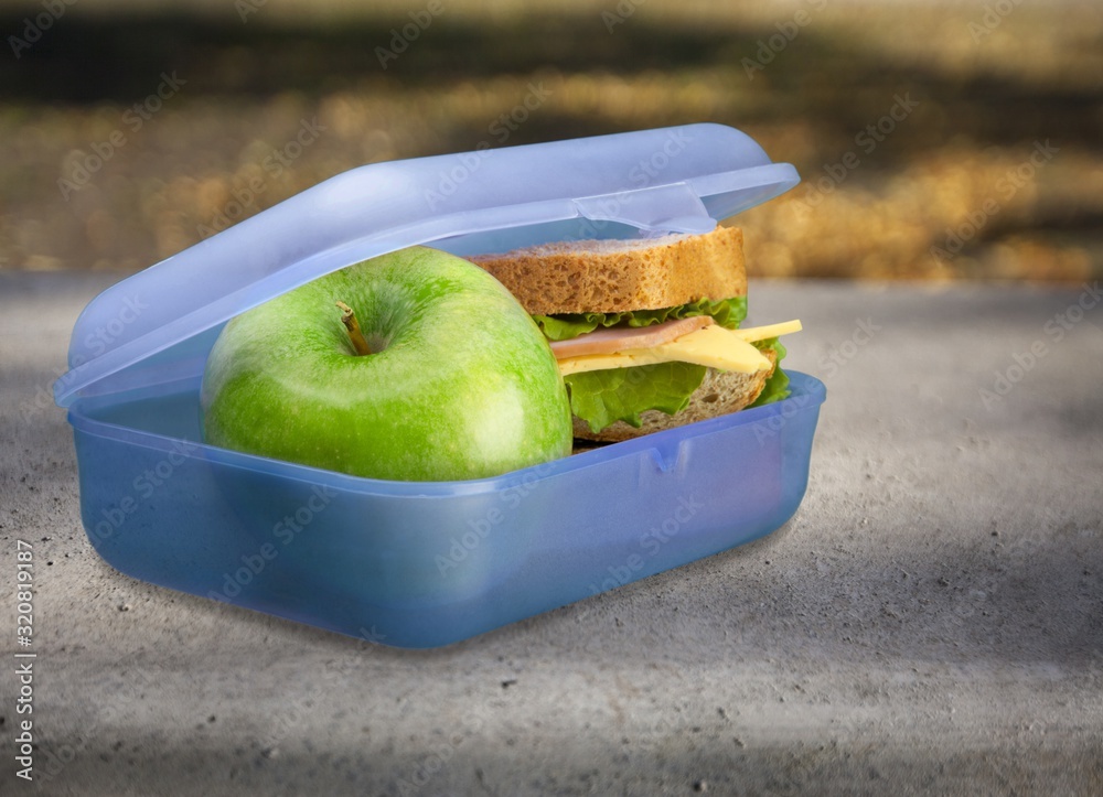 Lunchbox with an apple and sandwich on table
