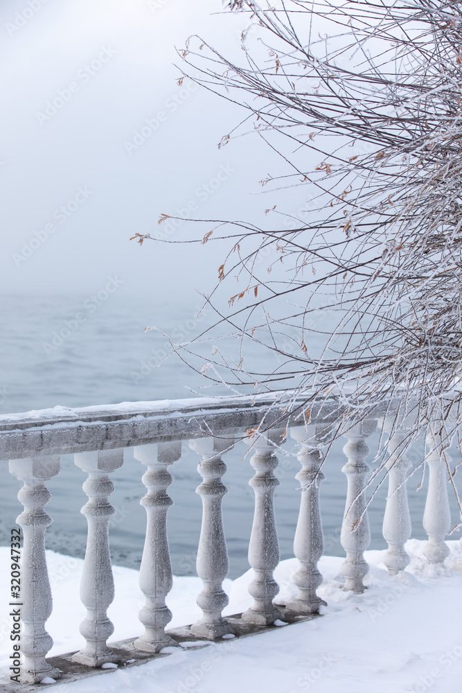 Frost and ice covered balusters on a lake shore in winter. Lake Baikal, Listvyanka, Siberia, Russia.