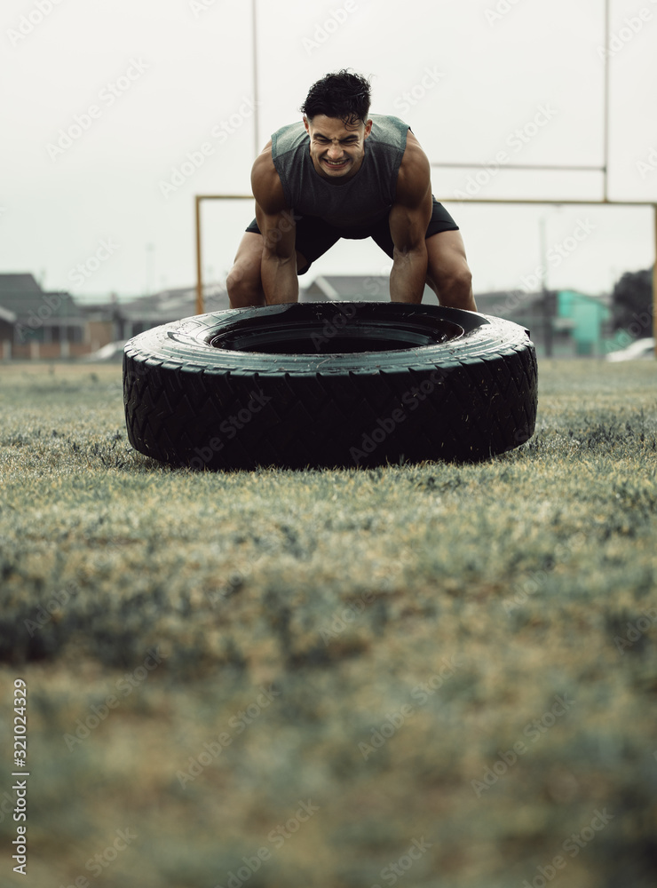 Muscular athlete doing a tire flip workout