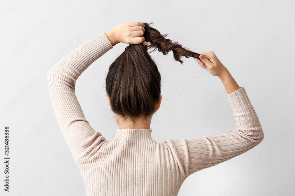 年轻女子在浅色背景下做头发