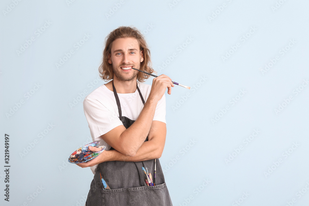 Portrait of young male artist on color background