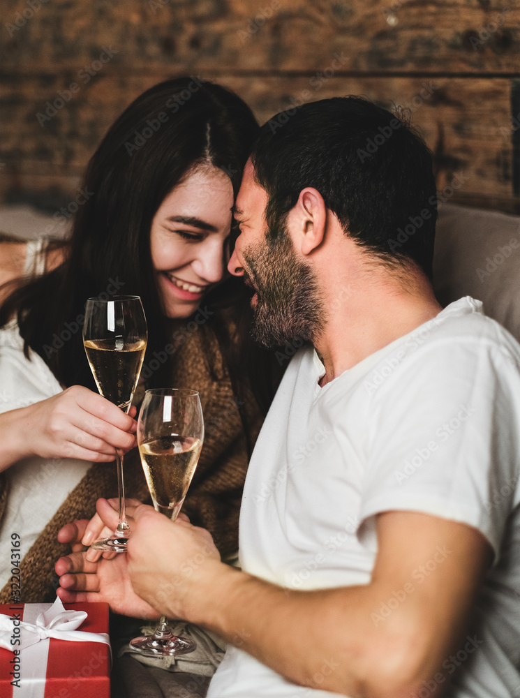 Young lovely happy caucasian couple holding glasses of champagne and laughing. Saint Valentines day 
