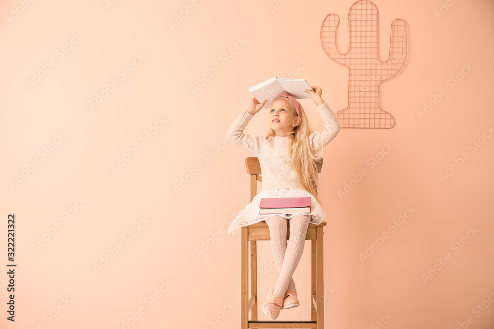 Little girl with books on color background