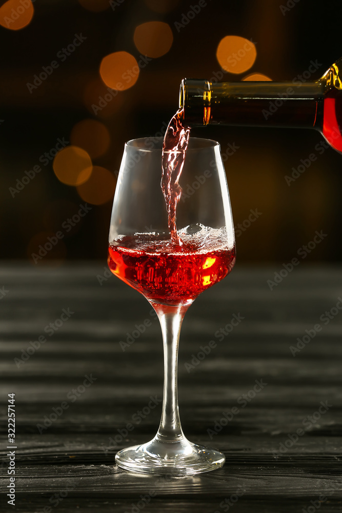把美味的葡萄酒从瓶子里倒进酒吧桌子上的杯子里