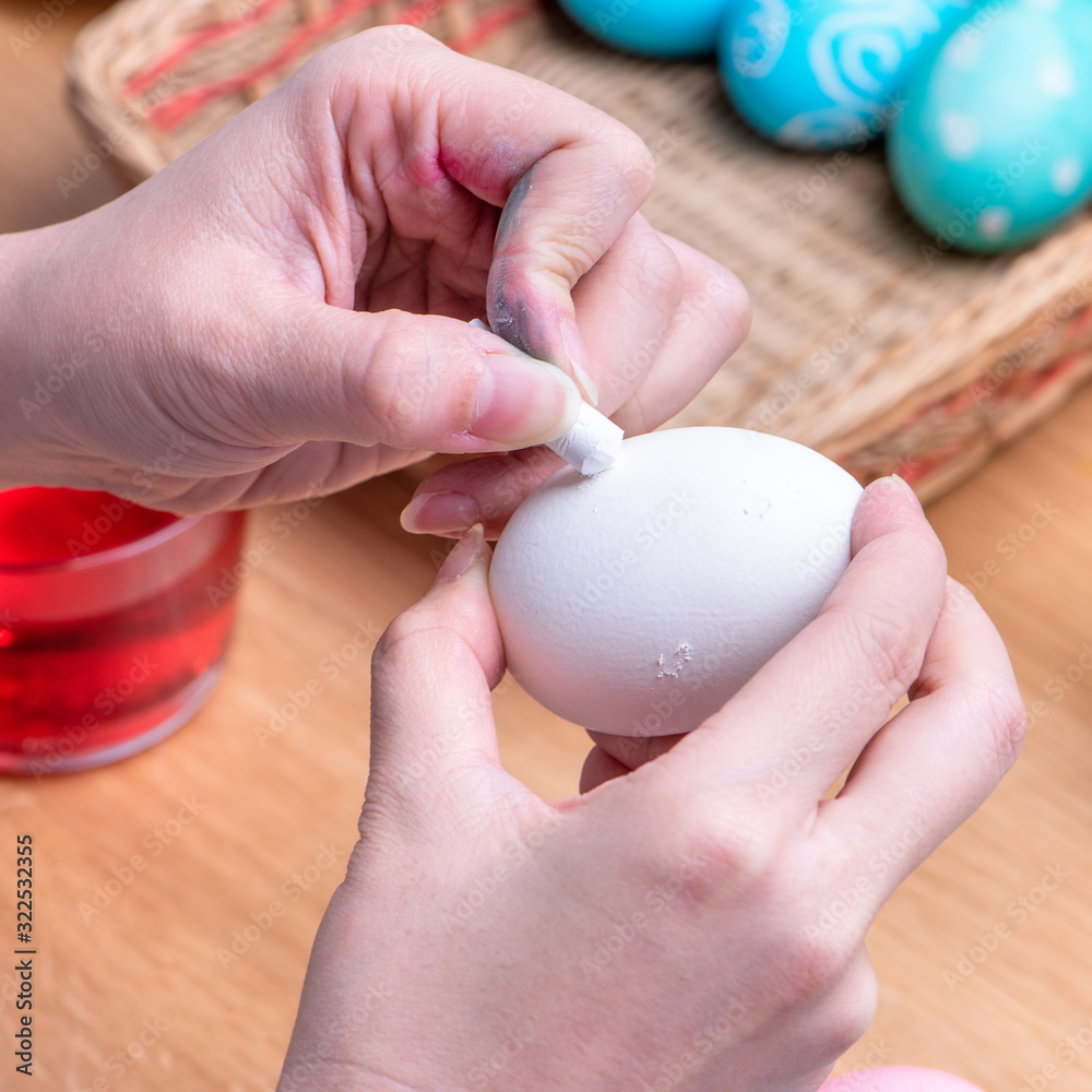 复活节彩蛋准备-年轻女子在染色colo之前用粉彩蜡笔画白色彩蛋