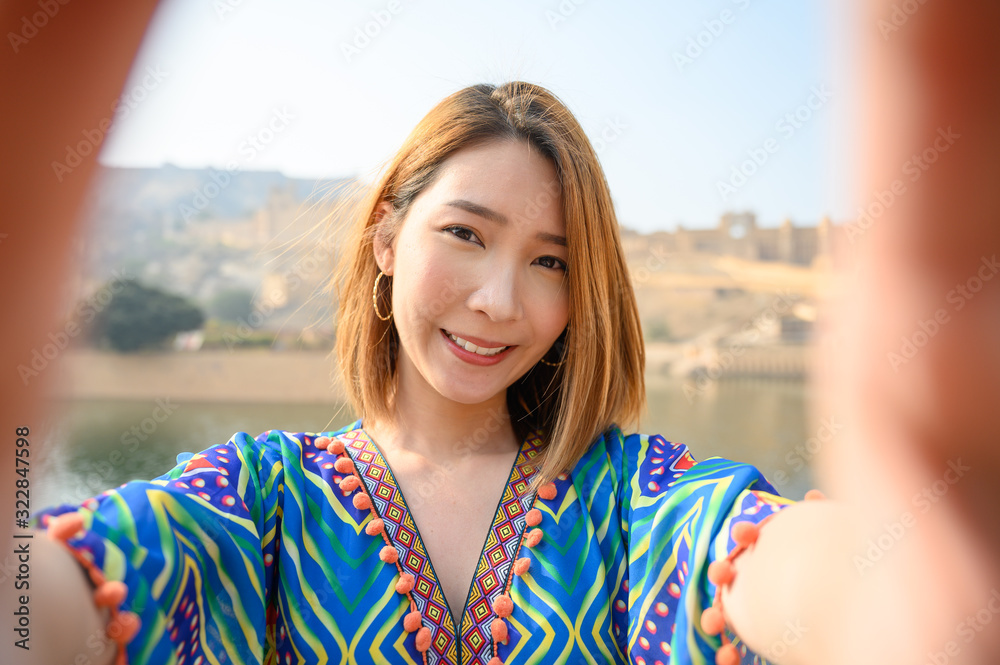 Young woman colorful dress selfie herself in front amber palace in Jaipur, rajasthan, India