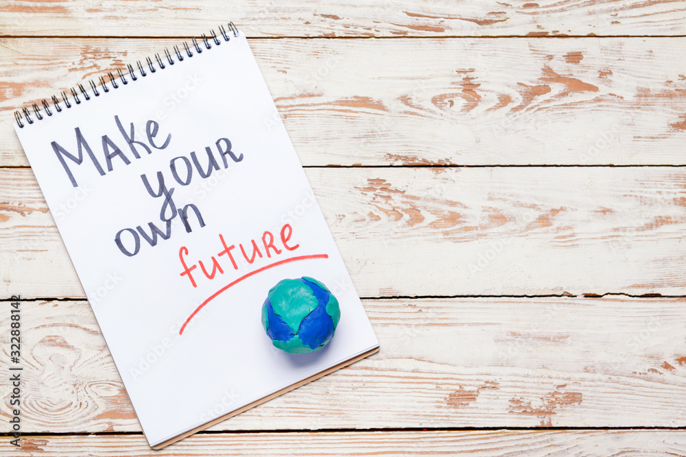 Notebook with text MAKE YOUR OWN FUTURE on wooden background. Earth Day celebration