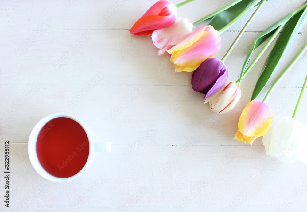 浪漫的背景，白色桌子上有一杯茶和郁金香。柔和的照片。贺卡风格，plac