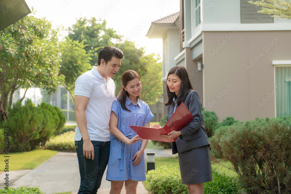 亚洲女性房地产经纪人向年轻的亚洲夫妇lo展示了她档案中的房屋细节