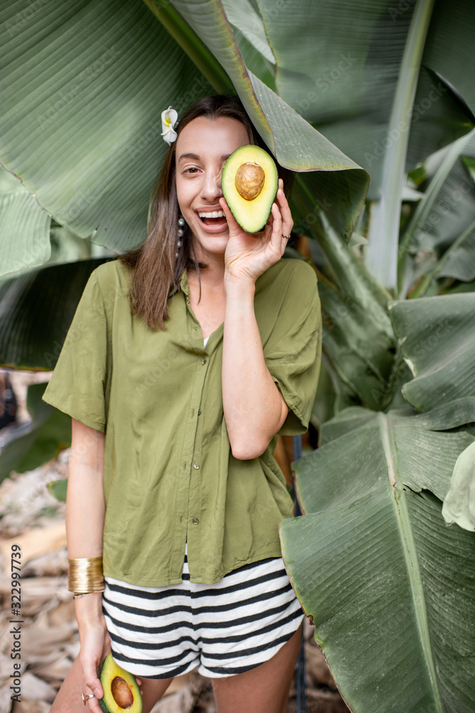 一个年轻可爱的女人的肖像，在户外的香蕉叶里放着鳄梨浆果片。概念