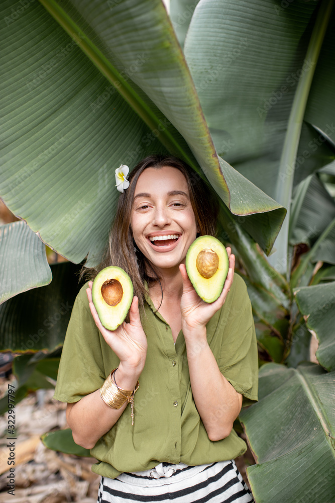 一个年轻可爱的女人的肖像，在户外的香蕉叶里放着鳄梨浆果片。概念