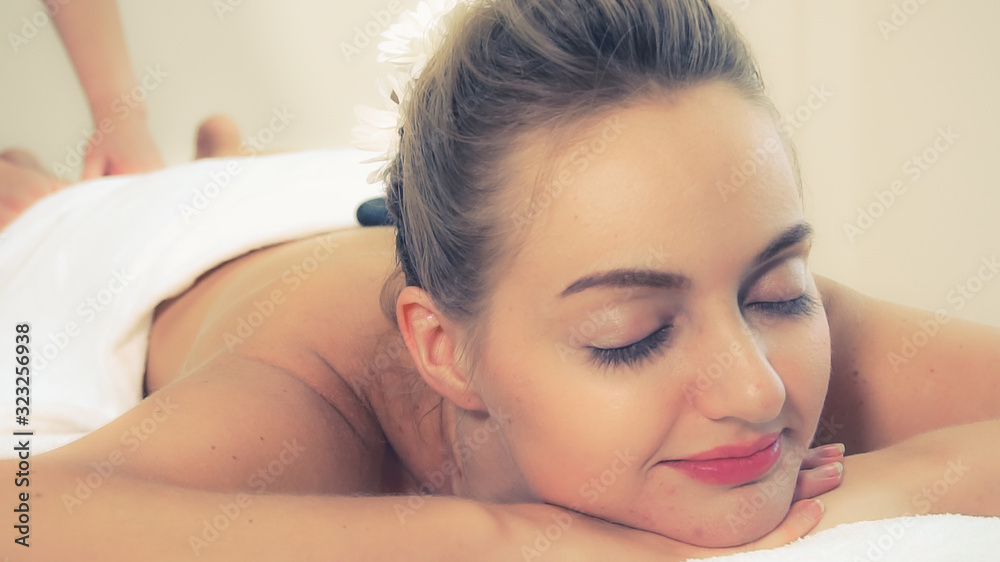Relaxed young woman lying on spa bed prepared for facial treatment and massage in luxury spa resort.