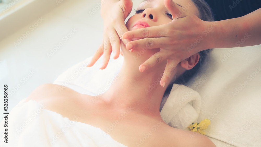 Relaxed woman lying on spa bed for facial and head massage spa treatment by massage therapist in a l