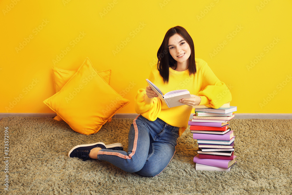 美丽的年轻女子，在彩色墙上拿着书