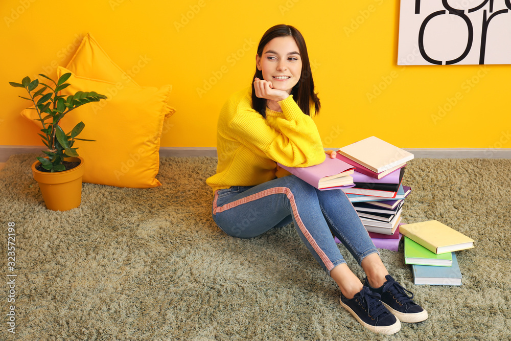 美丽的年轻女子在彩色墙附近拿着书