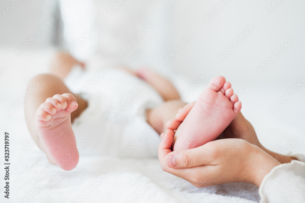 年轻的亚洲母亲在白色床上用爱抱着她的新生儿，母亲节概念