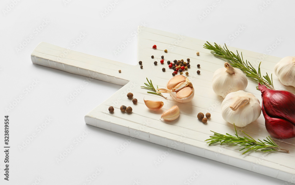 Board with garlic, spices and herbs on white background