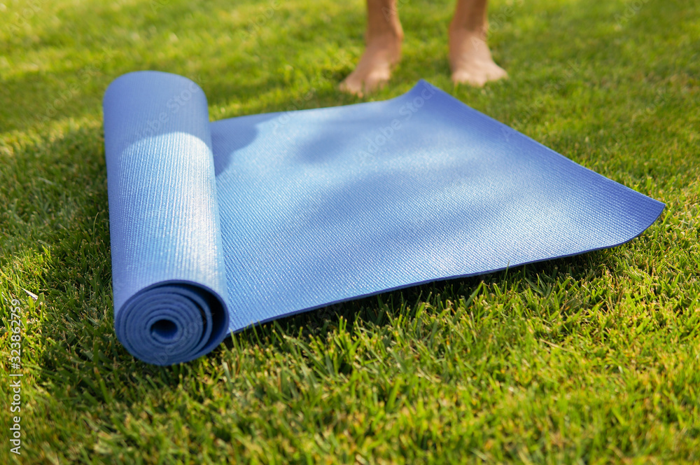 男子在阳光明媚的草地上进行户外瑜伽练习，专注于瑜伽垫