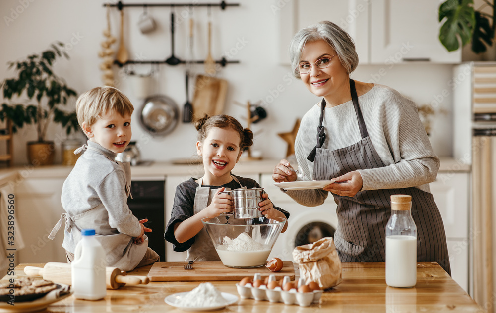 幸福家庭的祖母和孙子在厨房做饭，揉面团，烤饼干。