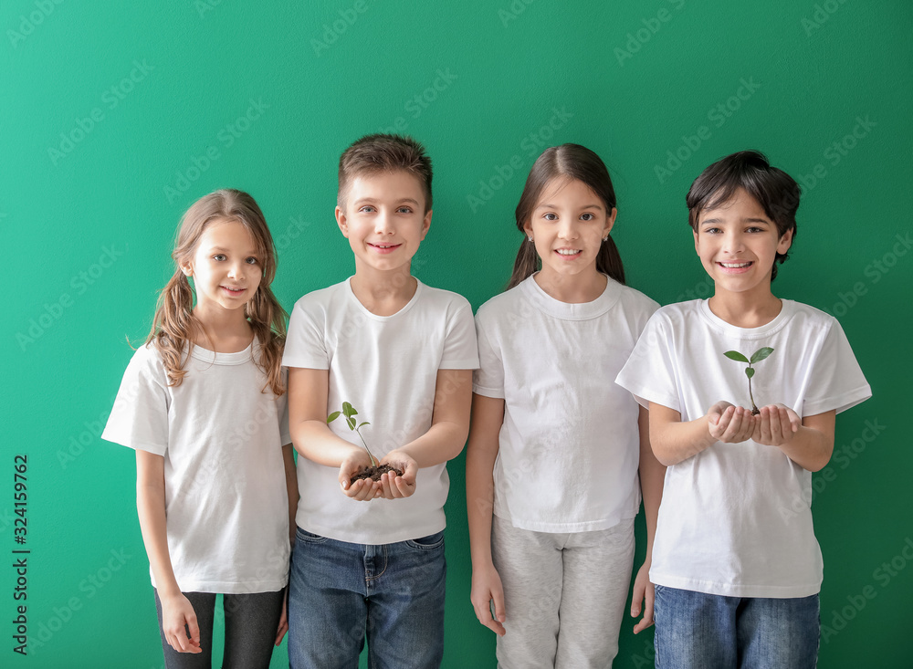 Little children with plants and soil on color background. Earth Day celebration