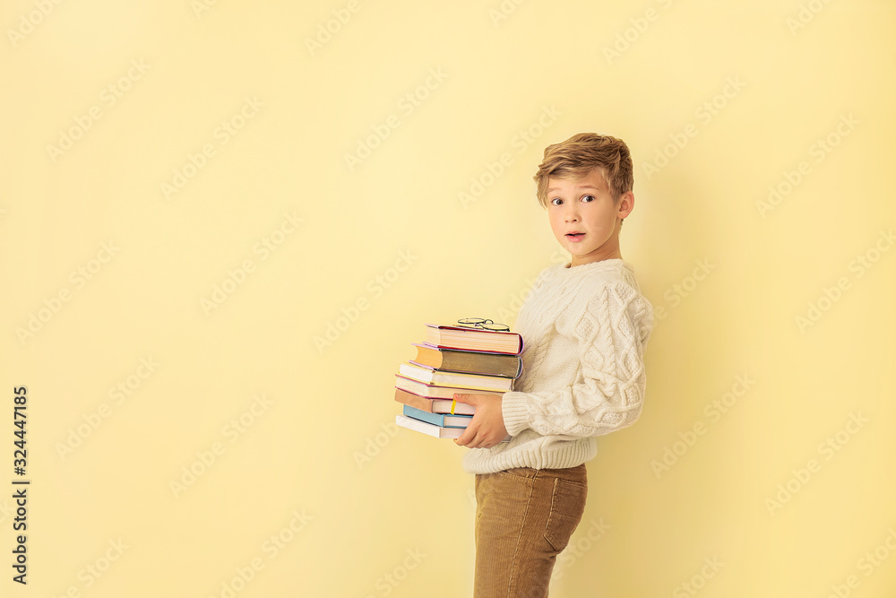 Surprised little boy with books on color background