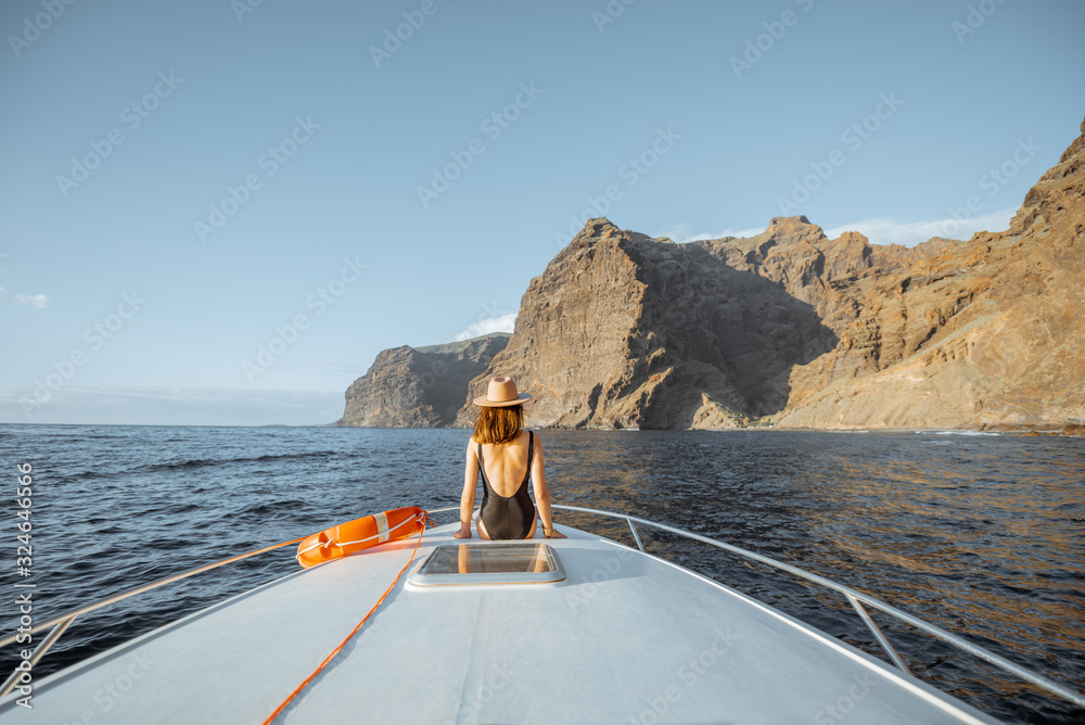 Woman enjoying ocean voyage sitting with lifebuoy on the yacht nose while sailing near the breathtak