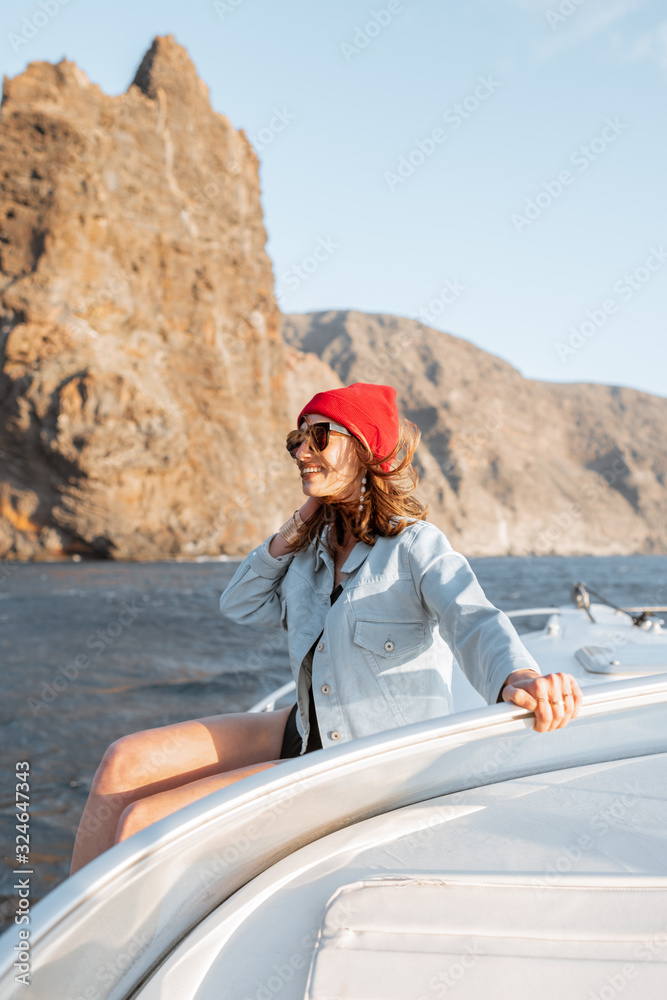 一名穿着休闲的女子在惊险的岩石海岸附近的游艇上享受海上航行