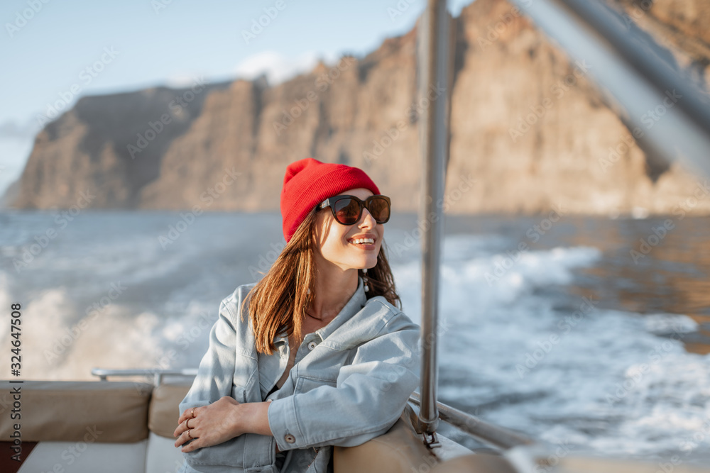 一位年轻的女旅行者的肖像，她戴着红帽子，穿着牛仔裤，在附近的游艇上航行