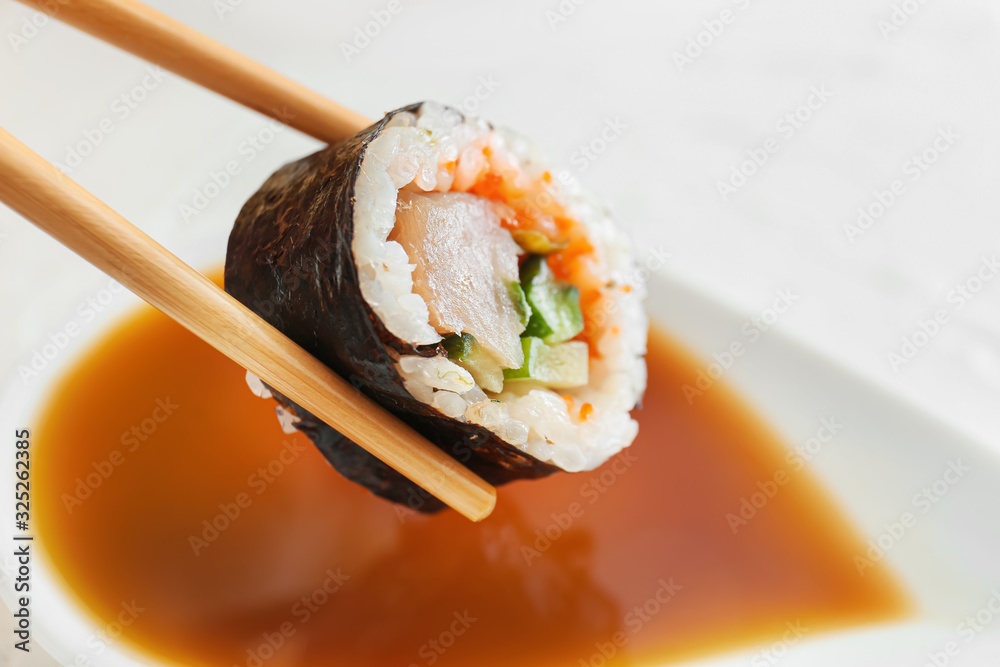 将美味的寿司卷蘸上酱油，特写