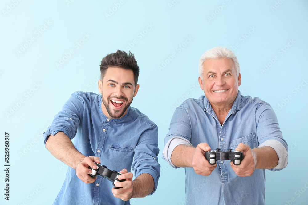 年轻人和他的父亲在彩色背景下玩电子游戏