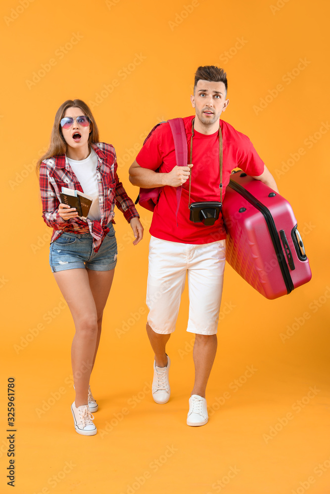 带着彩色背景行李的忧心忡忡的游客夫妇