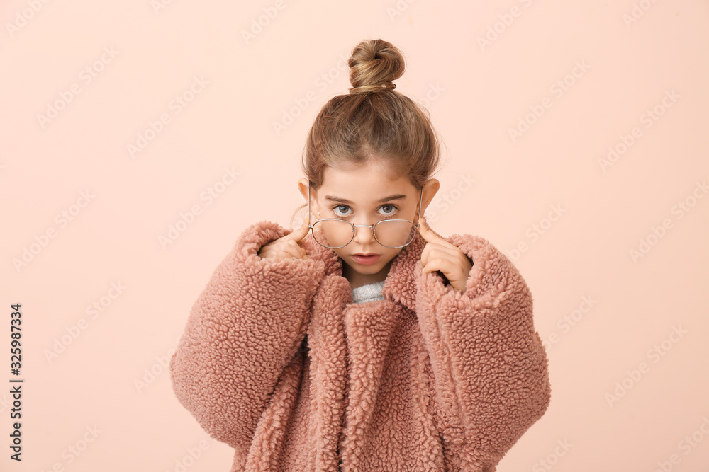 Cute little girl in winter clothes on color background