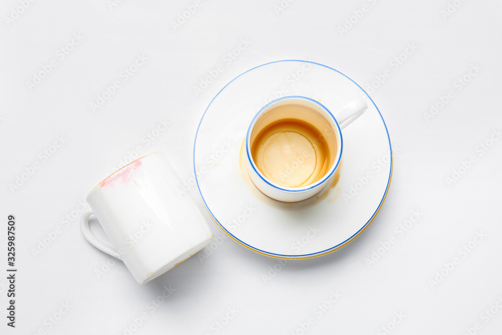 Dirty empty cups with saucer on white background