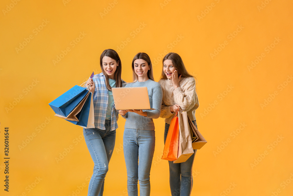 彩色背景下带笔记本电脑和购物袋的年轻女性