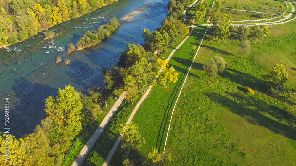 AERIAL: Flying above neat footpaths and big river in recreational park area