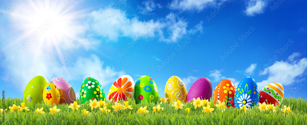 Colorful Easter eggs on green grass with spring flowers