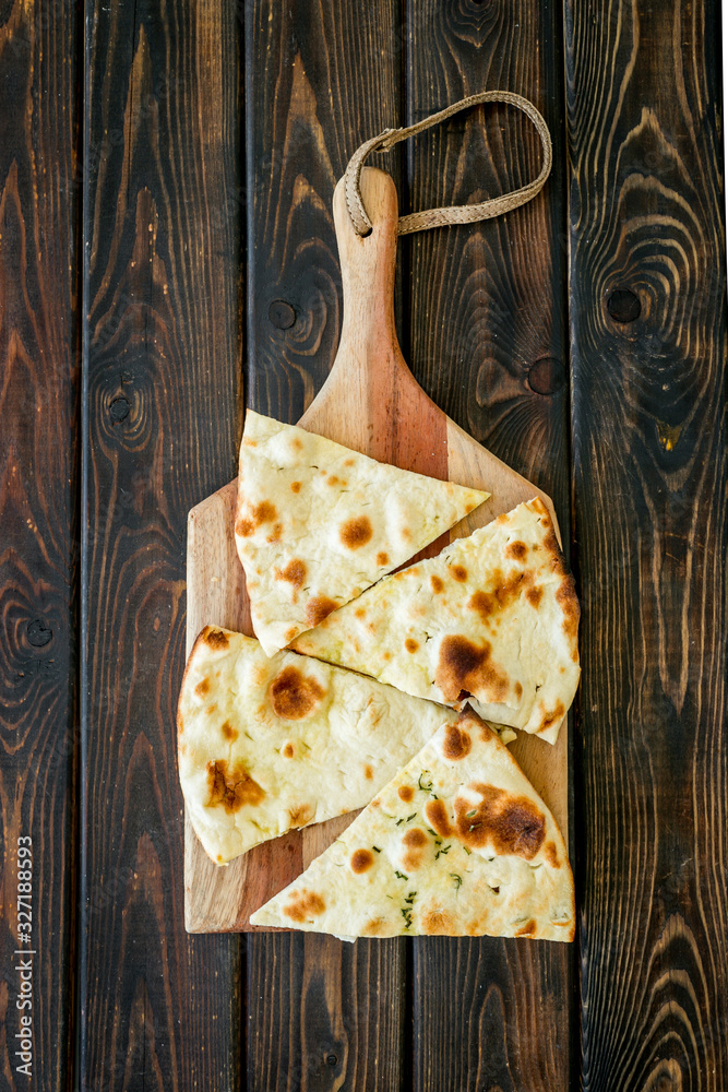 制作focaccia。传统的意大利面包放在深色木桌上的砧板上自上而下