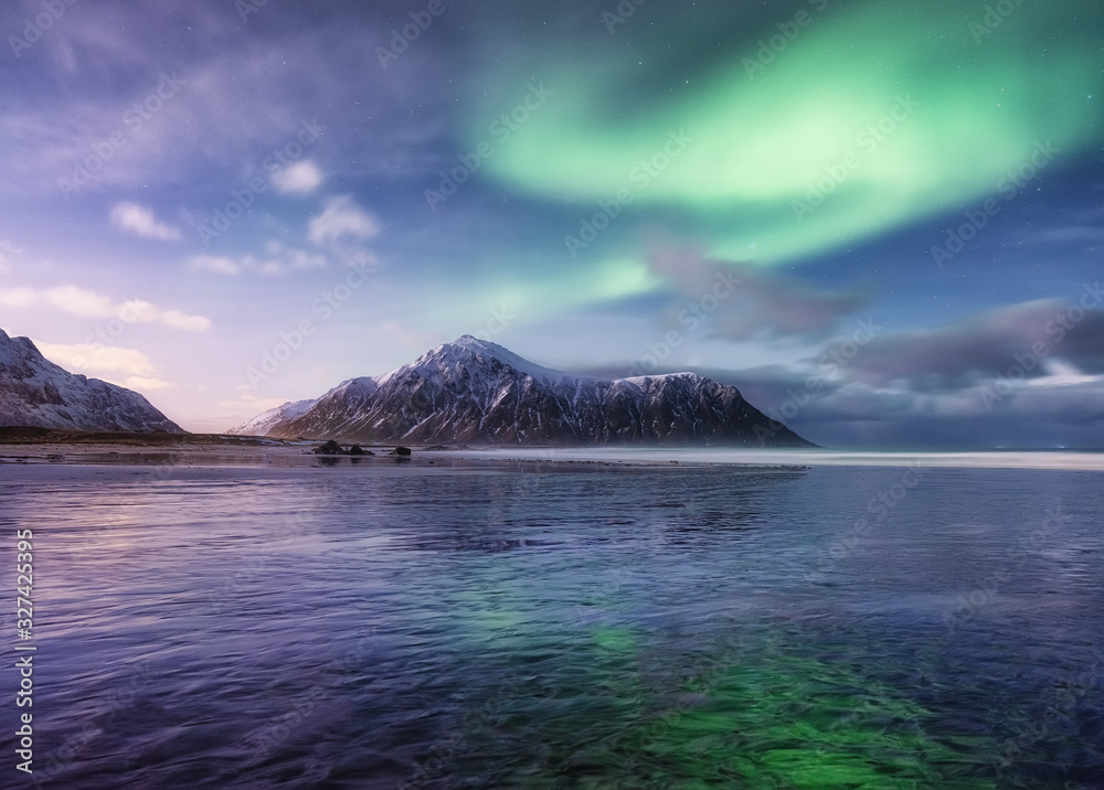 北极光。挪威罗弗敦群岛的斯卡桑登海滩。星星和北极光。反射