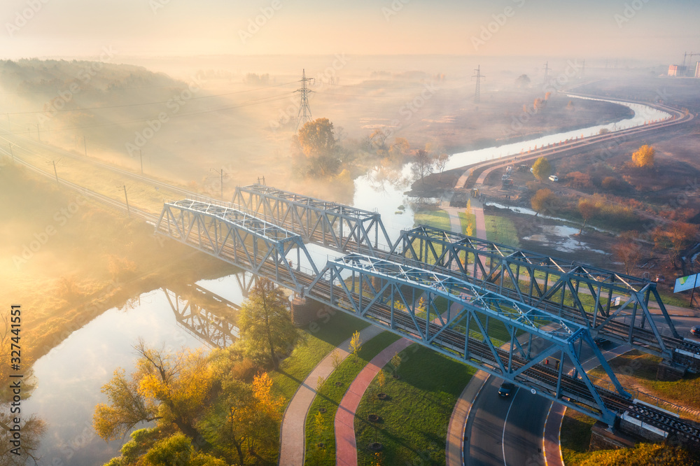 秋天日出时雾中美丽的铁路桥和河流鸟瞰图。工业景观