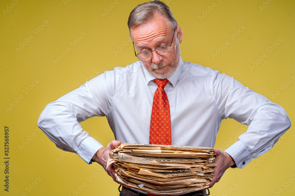 Mature businessman with old documents and bills. Isolated on yellow background