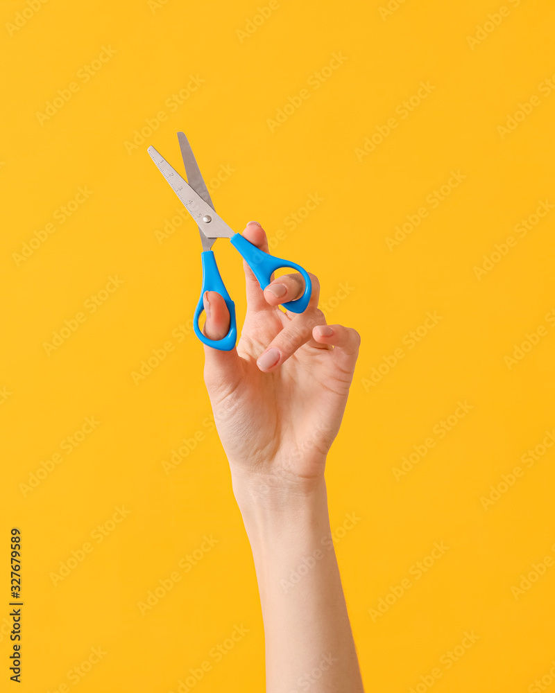 Hand with scissors on color background