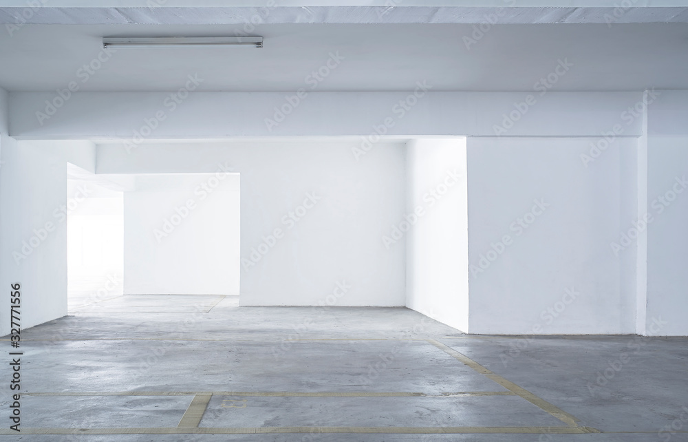 Empty parking lot with rough cement floor and white wall .