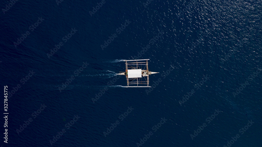 Aerial top down view of boat moving in open sea with clear and turquoise water on over coral reef,  