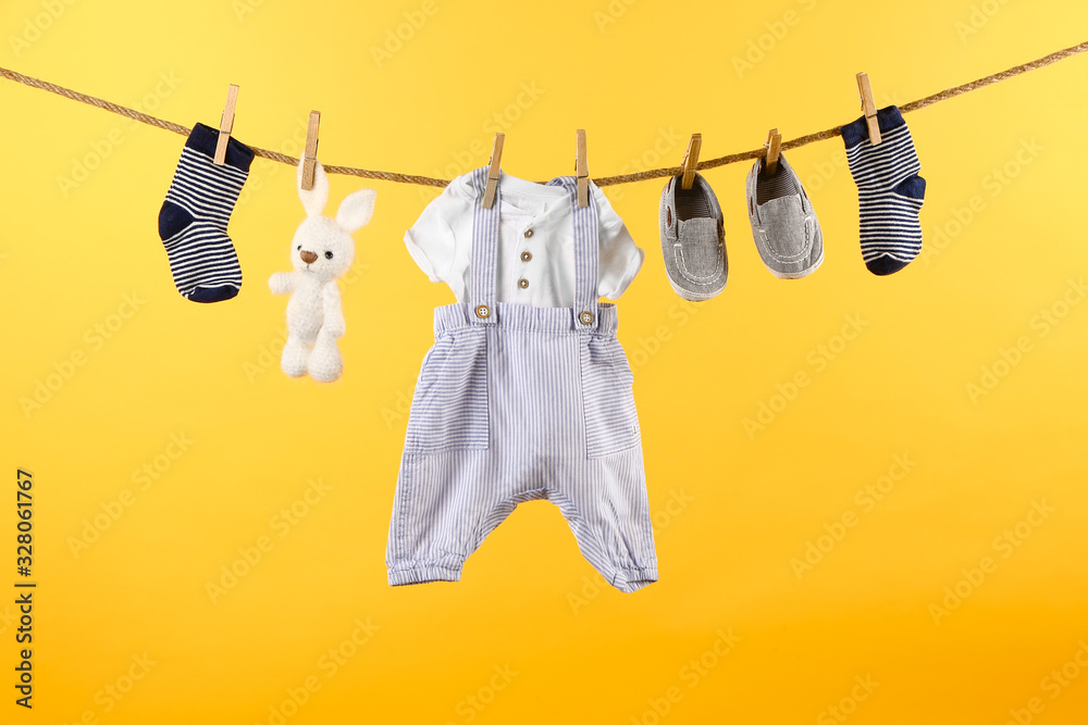 挂在绳子上的婴儿衣服和配饰，背景为彩色